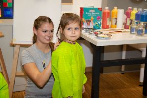 Kind wird mit Schutzkleiung für das malen vorbereitet