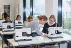 Schüler sitzen an Nähmaschinen